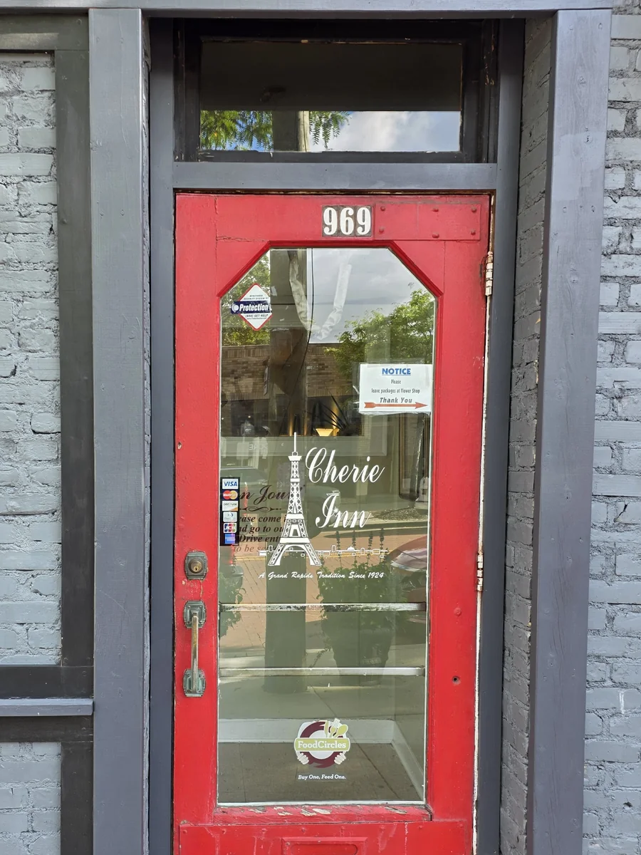 The red front door at 969, etched 'Cherie Inn — A Grand Rapids Tradition Since 1924' with an Eiffel Tower.